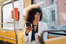 Young Businesswoman With Smart Phone And Coffee Cup Commuting In Bus