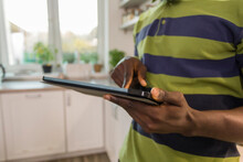 Hands Of Man Using Tablet PC In Kitchen At Home