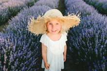 Smiling Cute Girl Wearing Straw Hat Standing In Lavender Field