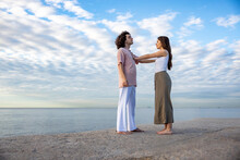 Young Couple Touching Each Other Standing On Pier By Sea