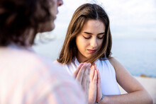 Young Woman Meditating With Hands Clasped By Boyfriend