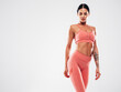 © halayalex - Tanned fitness woman in pink sports clothing. Sexy young beautiful model with perfect body.Female isolated on grey background in studio. Stretching out before training