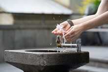 Closeup Photo Of Female Washing Hands In City Fountain In Outdoor At Day Time. Drinking Water Flowing Through City Saves In Hottest Summer Weather. Hydration And Aqua Balance Regulation For Health. 