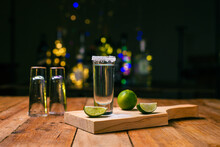 Tequila shots served in tequila glasses on a wooden table. Tequila shots with salt and lime on a bar table.