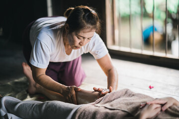 Wall Mural - Massage and spa relaxing treatment of office syndrome using hot stone traditional thai massage style. Asain female masseuse doing foot massage treat stress for woman.