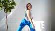 © Ulia Koltyrina - Modern dance, stylish young brunette in baggy blue pants dancing in jazz-funk style. Stylish and youthful. The dance hall is illuminated by sunlight, bright colors