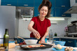 © _KUBE_ - Portrait of a young woman cooking a pizza. Kitchen on the background. Homemade cooking concept
