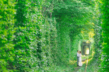 a tree tunnel and a railroad track. the couple in love stand fac