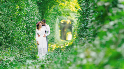 The guy hugs the girl from the back side. tunnel of trees and gr