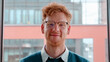 Young ginger irish man in glasses smiling with pleased happy expression and looking at camera portrait. Millennial male freelancer successful entrepreneur,young businessman standing in office. Slow mo