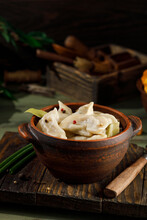 ready-made dumplings with potatoes and mushrooms in a plate on the table. With smoke. Vertical photo