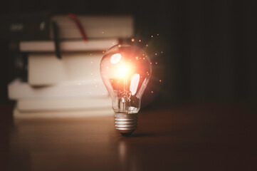Poster - Orange light glowing from lightbulb infant of heap of books for study and learning can make creative thinking idea and knowledge to problem solving concept.