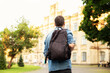 © stock_studio - Student university standing with his back to the camera and his backpack on one shoulder and walking in university campus, education concept. Young man walking down street with a backpack. Back view.