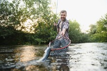 Fisherman Picking Up Big Rainbow Trout From His Fishing Net