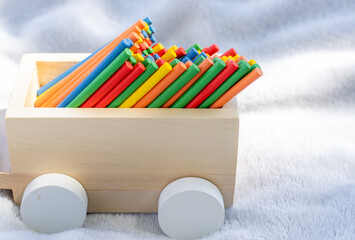 wooden train wagon full of counting colorful sticks.multicolor eco wood material match stick for learning mathematics in primary school on grey blanket,green grass,sunshine.back to school concept,fall
