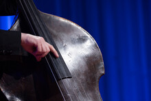 A Hand Of An Acoustic Double Bass Player Playing The Instrument During A Live Show On A Stage With A Blue Background Nr.3