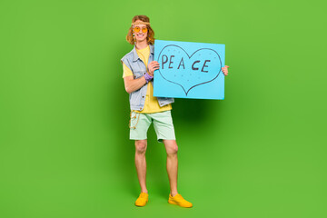 Poster - Full length body size view of attractive cheerful guy holding paper peace sign isolated over bright green color background