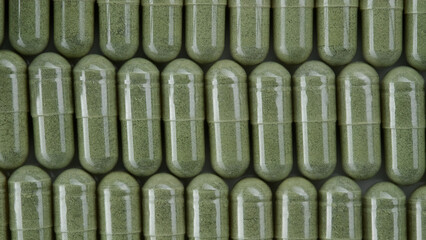 Wall Mural - Green capsules. Superfood moringa capsules top view. Spirulina, chlorella capsules