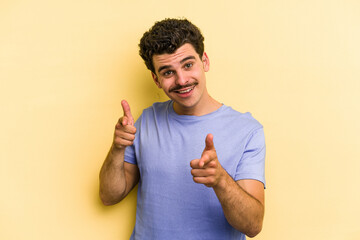 Wall Mural - Young caucasian man isolated on yellow background pointing to front with fingers.