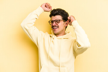 Wall Mural - Young caucasian man isolated on yellow background celebrating a special day, jumps and raise arms with energy.