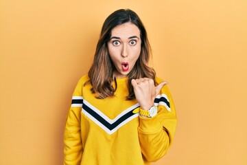 Poster - Young hispanic girl wearing casual clothes surprised pointing with hand finger to the side, open mouth amazed expression.