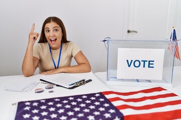 Sticker - Young brunette woman at political election sitting by ballot pointing finger up with successful idea. exited and happy. number one.