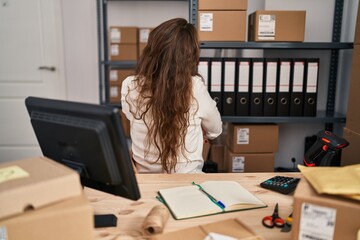 Wall Mural - Young hispanic woman working at small business ecommerce standing backwards looking away with crossed arms