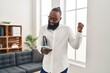 © Krakenimages.com - African american man working at therapy office using smartphone screaming proud, celebrating victory and success very excited with raised arm