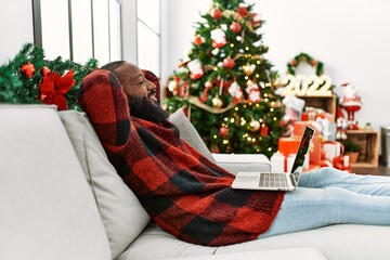 Sticker - Young african american man relaxed with hands on head sitting by christmas tree at home