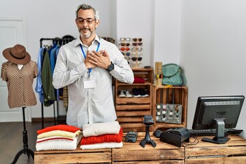 Poster - Middle age hispanic man working as manager at retail boutique smiling with hands on chest with closed eyes and grateful gesture on face. health concept.