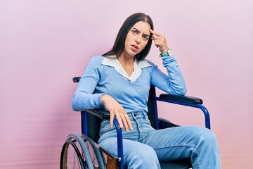 Wall Mural - Beautiful woman with blue eyes sitting on wheelchair pointing unhappy to pimple on forehead, ugly infection of blackhead. acne and skin problem