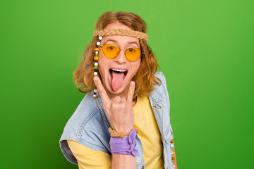 Poster - Portrait of carefree person tongue out arm fingers demonstrate heavy metal symbol isolated on green color background