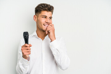 Young singer caucasian man isolated on white background relaxed thinking about something looking at a copy space.