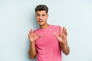 Young caucasian man isolated on blue background rejecting someone showing a gesture of disgust.