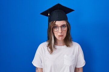 Wall Mural - Blonde caucasian woman wearing graduation cap depressed and worry for distress, crying angry and afraid. sad expression.