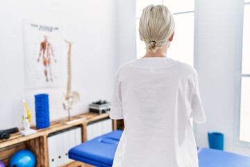 Sticker - Young caucasian woman working at pain recovery clinic standing backwards looking away with crossed arms