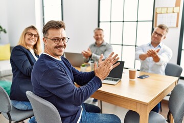 Sticker - Group of middle age business workers smiling happy. Sitting on the table clapping and looking to the camera at the office.