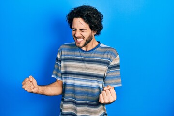 Poster - Handsome hispanic man wearing casual clothes over pink background very happy and excited doing winner gesture with arms raised, smiling and screaming for success. celebration concept.