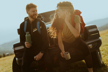 Wall Mural - Young couple relaxing on a terrain vehicle hood at countryside