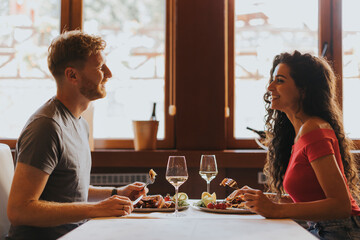 Wall Mural - Young couple having lunch with white wine in the restaurant