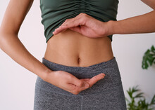 Close Up Of A Young Multi-ethnic Woman's Stomach Cupped By Her Hands