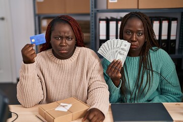 Sticker - Two african women working at small business ecommerce holding credit card and banknotes depressed and worry for distress, crying angry and afraid. sad expression.