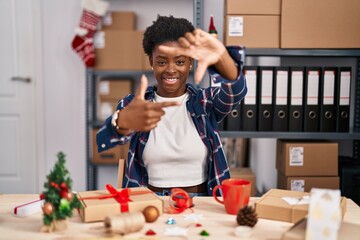 Poster - African american woman working at small business doing christmas decoration smiling making frame with hands and fingers with happy face. creativity and photography concept.