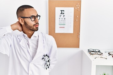 Poster - African american optician man standing by eyesight test suffering of neck ache injury, touching neck with hand, muscular pain