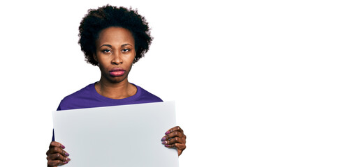 Wall Mural - African american woman with afro hair holding blank empty banner skeptic and nervous, frowning upset because of problem. negative person.