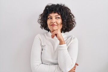 Sticker - Hispanic woman with curly hair standing over isolated background with hand on chin thinking about question, pensive expression. smiling and thoughtful face. doubt concept.