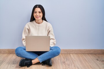 Sticker - Young woman using laptop sitting on the floor at home with a happy and cool smile on face. lucky person.