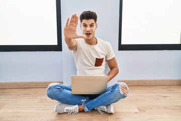 Sticker - Young hispanic man using laptop at home doing stop gesture with hands palms, angry and frustration expression