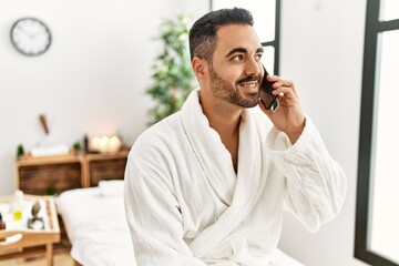 Canvas Print - Young hispanic man wearing bathrobe talking on the smartphone at beauty center