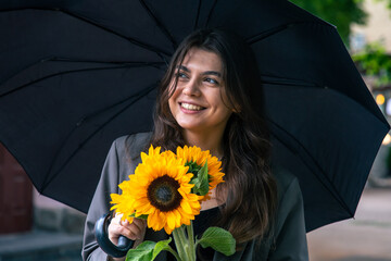 Wall Mural - A young woman with a bouquet of sunflowers under an umbrella in rainy weather.